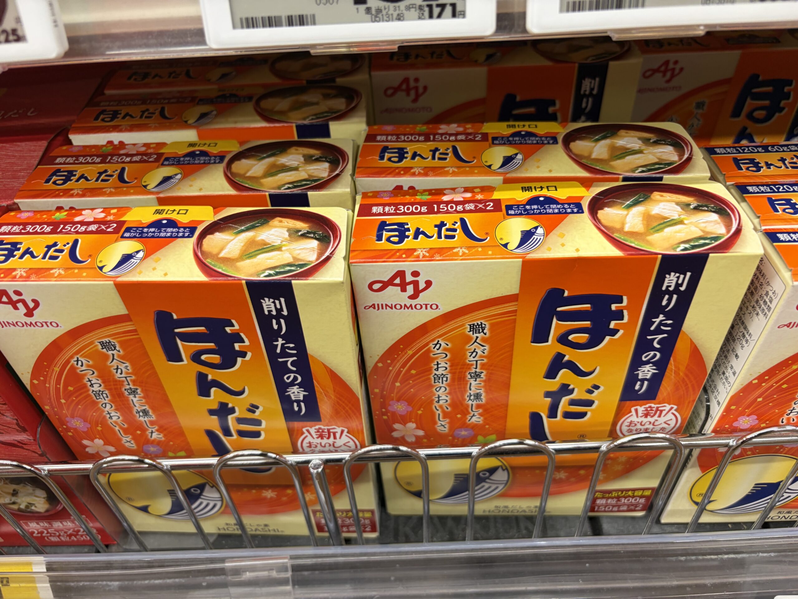 Boxes of instant dashi granules on a supermarket shelf, showing a bonito fish illustration and a bowl of miso soup