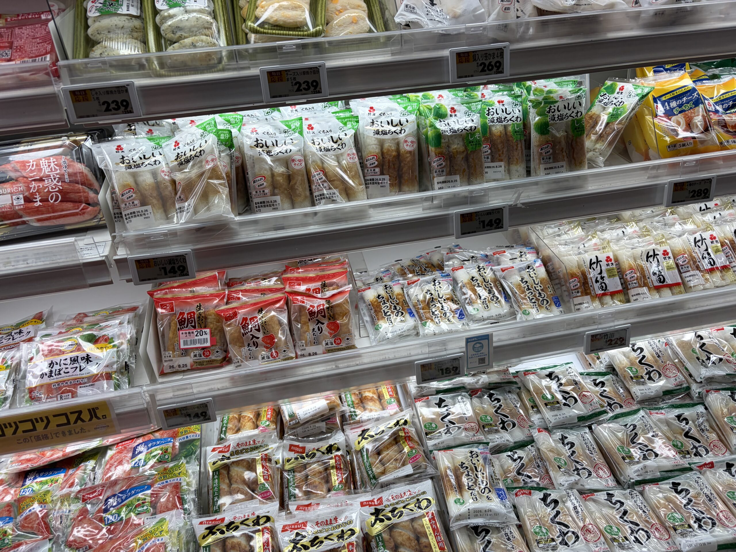A Japanese supermarket refrigerated shelf filled with chikuwa, kamaboko and imitation crab sticks, all made from ground fish